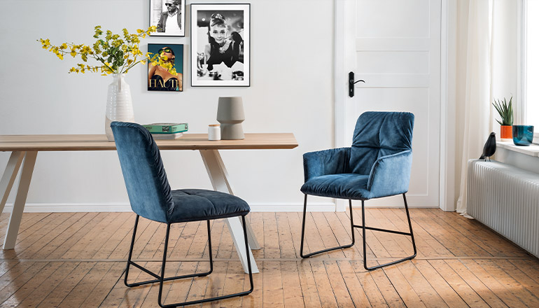 Zwei blaue Esszimmerstühle stehen an einem Esstisch im Skandi-Look der Marke Raumfreunde