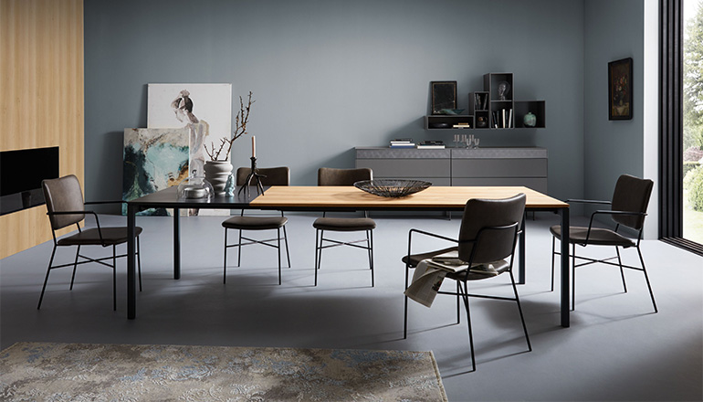 Minimalistisches Esszimmer mit Tisch aus Holz und Keramik, Stühlen aus Leder und einer Kommode aus Lack
