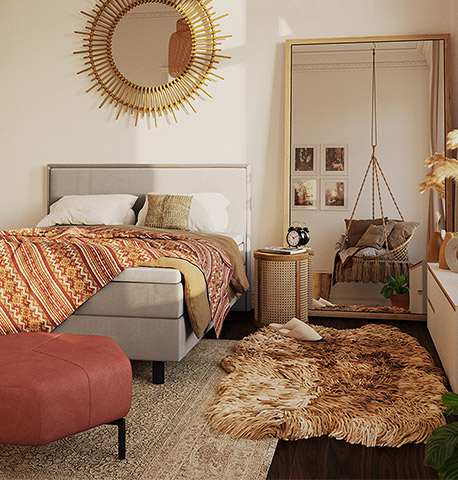 Schlafzimmer mit vielen Textilien im Boho Wohnstil: Schaffell, Boxspringbett aus Stoff, Kommode aus Holz und Hocker aus Velours