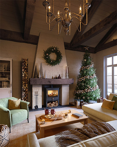 Klassisches Wohnzimmer mit grünem Sessel, Kamin, Weihnachtsbaum und weißer Wohnlandschaft
