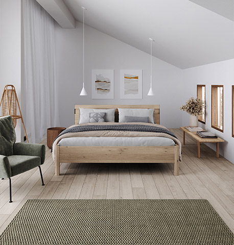 Helles Schlafzimmer mit schlichtem Bett und einem gemütlichen, grünen Sessel