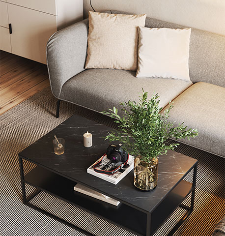 Beige-farbenes Sofa mit zwei Kissen vor schwarzem Couchtisch